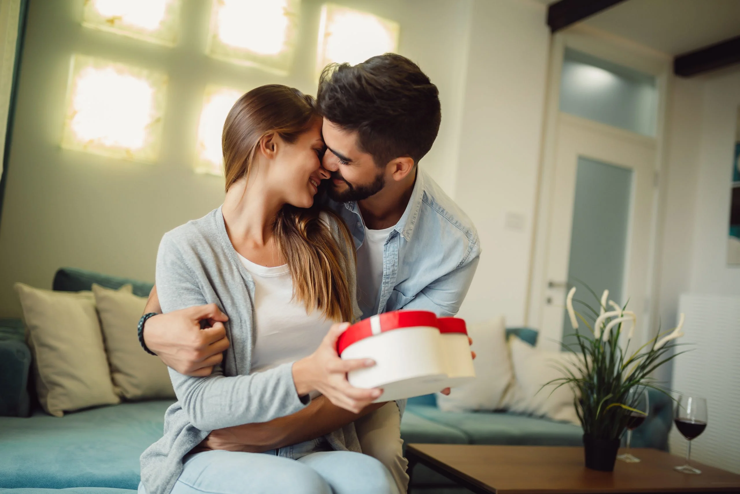 Portrait of young couple in love, celebrating anniversary and exchanging gifts